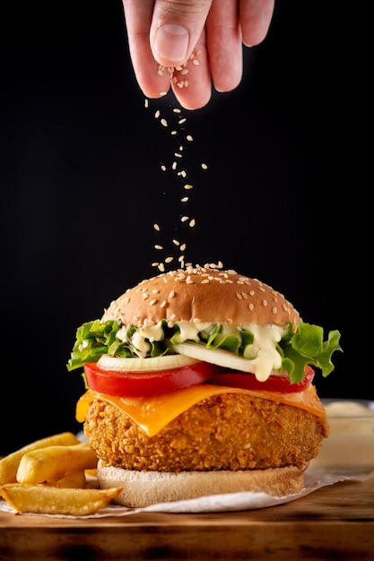 Verter semillas de sésamo en una hamburguesa de pollo crujiente