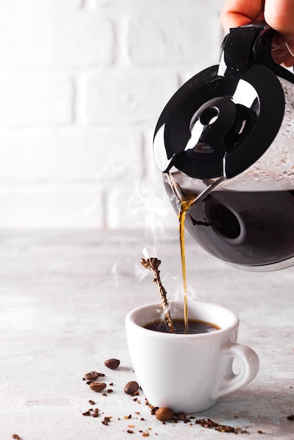 Verter una taza de café caliente en el vaso para el desayuno.