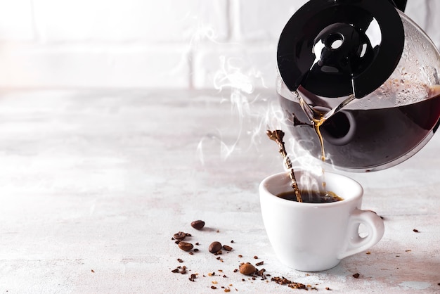 Verter una taza de café caliente en el vaso para el desayuno.