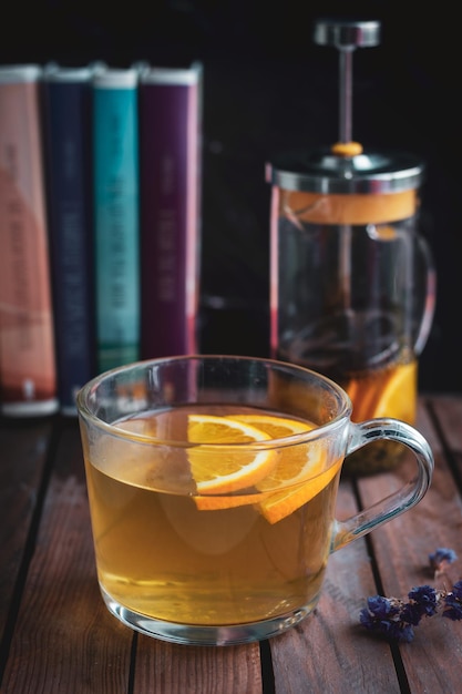 Verter té negro en un vaso de vidrio sobre una mesa de madera