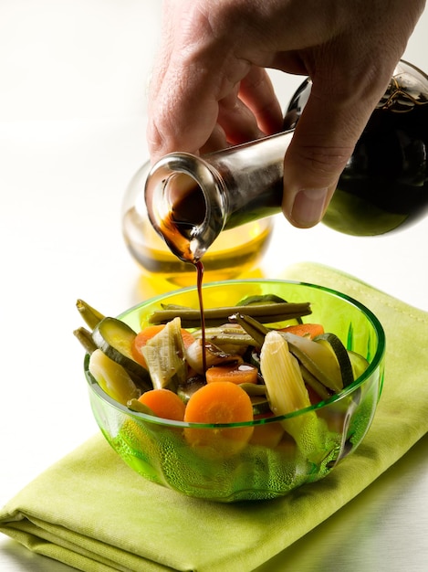 Verter vinagre balsámico sobre ensalada de verduras al vapor