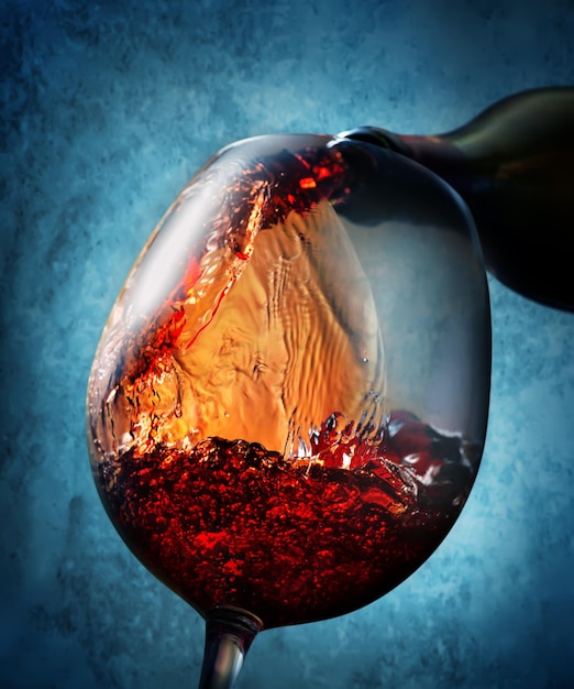 Verter el vino de la botella en una copa de vino sobre fondo azul.