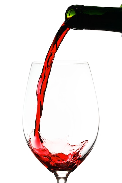Verter el vino tinto en vidrio aislado en la pared blanca