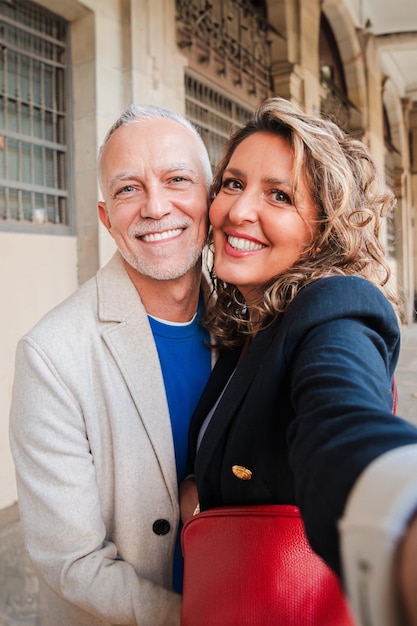 Vertical afetuoso meio adulto casado se divertindo tirando um retrato selfie juntos em um