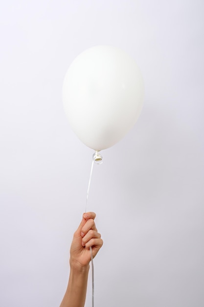 Vertical un globo blanco mínimo en la mano sobre fondo blanco copia espacio elemento de decoraciones para fiesta de cumpleaños festival de bodas