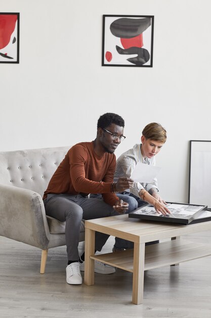 Vertical del hombre afroamericano hablando con la directora de la galería de arte femenina mientras se habla de pinturas y planificación de exposiciones en el museo