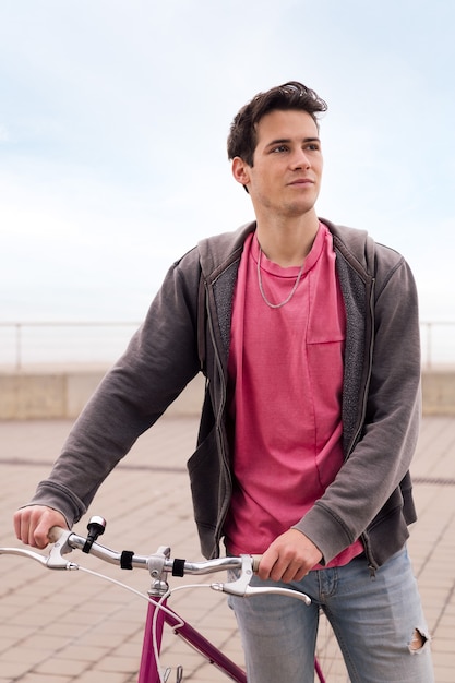 Vertical retrato de un apuesto joven caminando con una bicicleta vintage