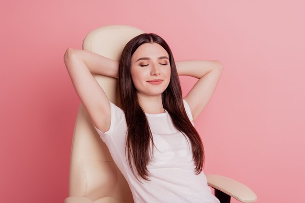 Foto vertical retrato de bastante joven dama sonriente feliz sentado en una silla descansar relajarse dormir aislado sobre fondo de color rosa