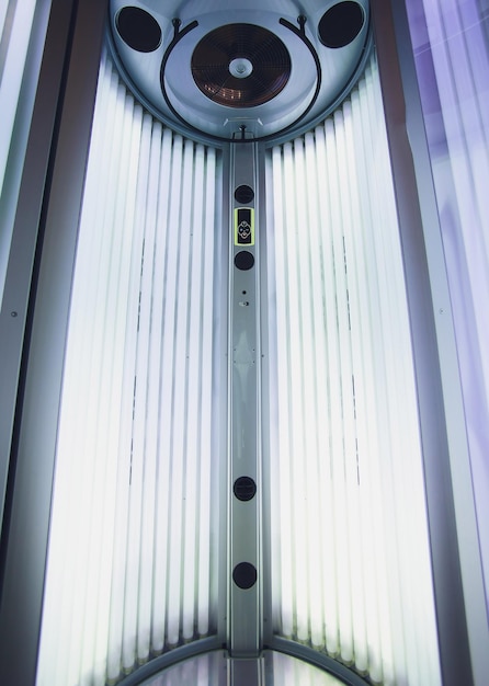 Foto vertical tanning turbo solarium light machine com lâmpadas ultravioletas de luz azul brilhante para bronzeamento e cuidados com a pele tanning vazio solário moderno dentro solário aberto porta do solário painel de controle no lado