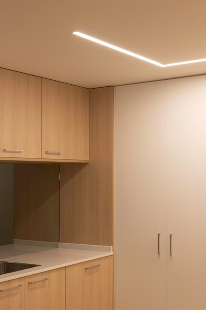 Vertikale Ansicht der modernen, minimalen Holz- und weißen Küche beleuchtet