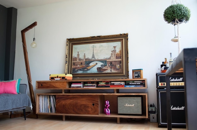 Vertikale Ansicht des gemütlichen Wohnzimmers mit Vinyl-Player auf hölzernem Sideboard mit Büchern