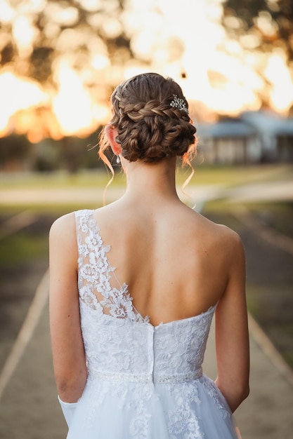 Vertikale Aufnahme einer jungen Frau in einem Brautkleid mit Haaren im Freien