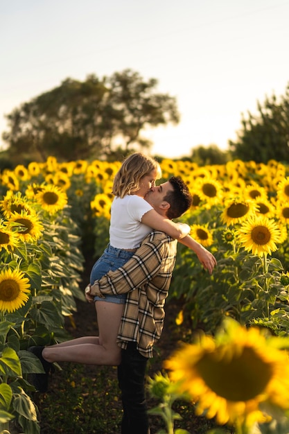 Vertikale Aufnahme eines kaukasischen schönen Paares auf dem Sonnenblumenfeld in Spanien