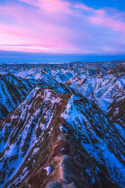 Vertikale Aufnahme eines rosa Sonnenaufgangs über schneebedeckten Gipfeln im Badlands National Park South Dakota