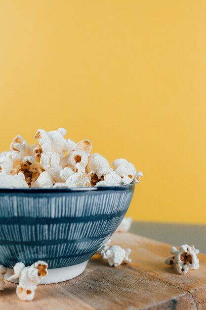 Vertikale Aufnahme von Popcorn in einer Keramikschale, die auf ein Holzbrett gelegt wird