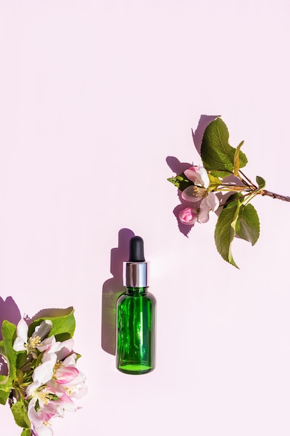 Vertikale Draufsicht einer Flasche mit einer Pipette mit einem feuchtigkeitsspendenden Serum zur Verjüngung der Gesichtshaut Naturkosmetik Rosa Apfelblüten