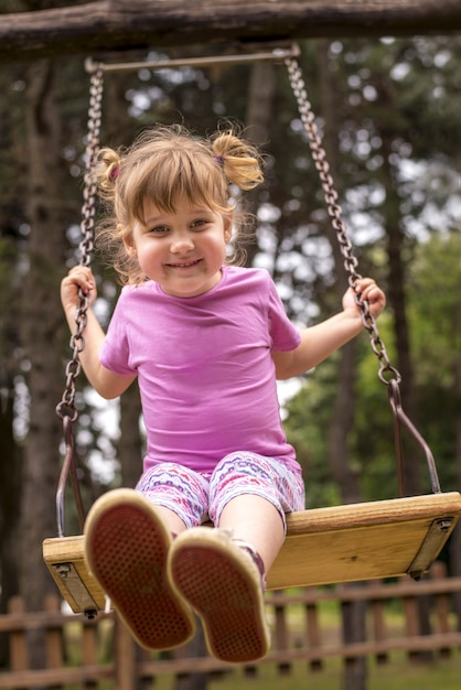 Vertikale flache Fokusaufnahme einer jungen Frau, die auf einer Schaukel auf dem Spielplatz schwingt