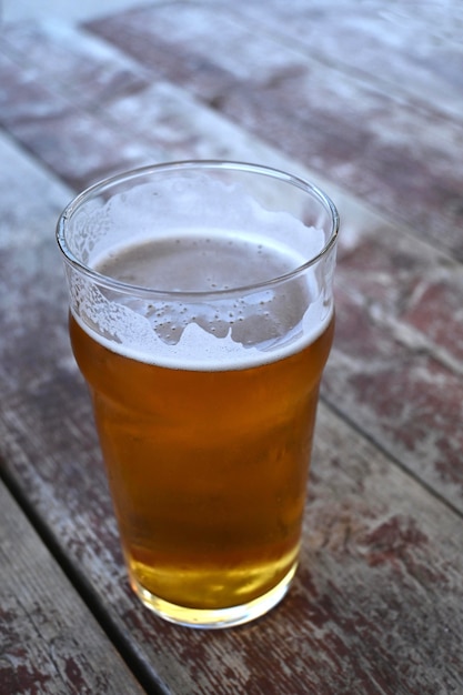 Vertikale Nahaufnahme eines Bierglases auf einem Holztisch