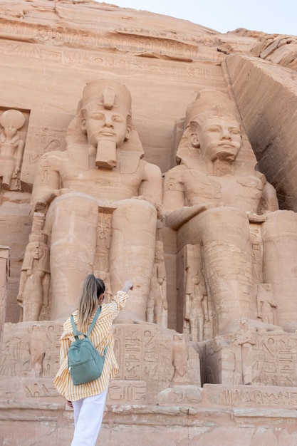 Vertikale, niedrige Winkelansicht der Touristenfrau von hinten, die den Tempel Abu Simbel Nefertari aus der Nähe zeigt