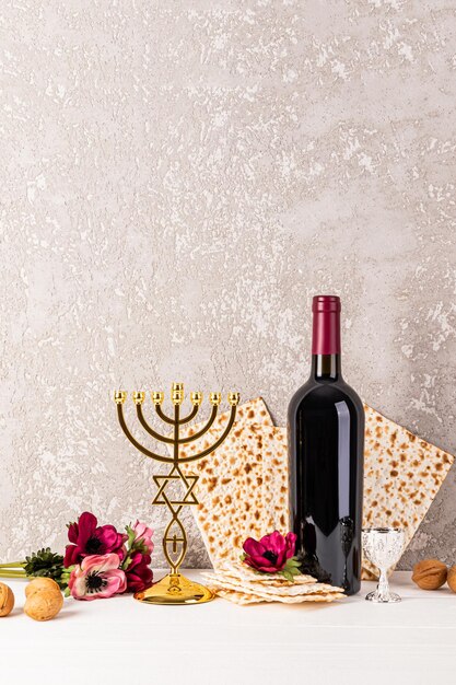 Vertikaler festlicher Hintergrund für das jüdische Passahfeiertag mit traditionellem Matzothbrot, Rotweinblumen und goldenem kleinen Kerzenstock.