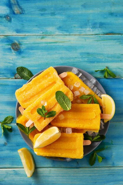 Vertikaler Schuss des gelben erfrischenden Eissorbetes auf blauem rustikalem Hintergrund