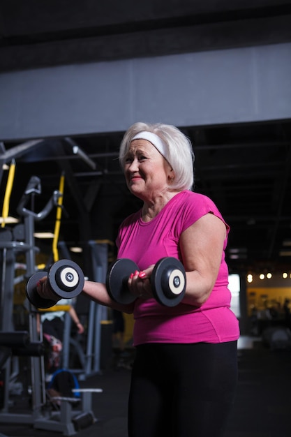 Vertikaler Schuss einer glücklichen Seniorin, die beim Training mit Hanteln lacht