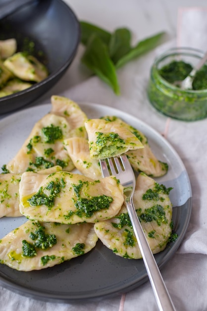 Vertikaler Schuss köstlicher Ravioli mit Pesto-Sauce auf einem Teller auf dem Tisch