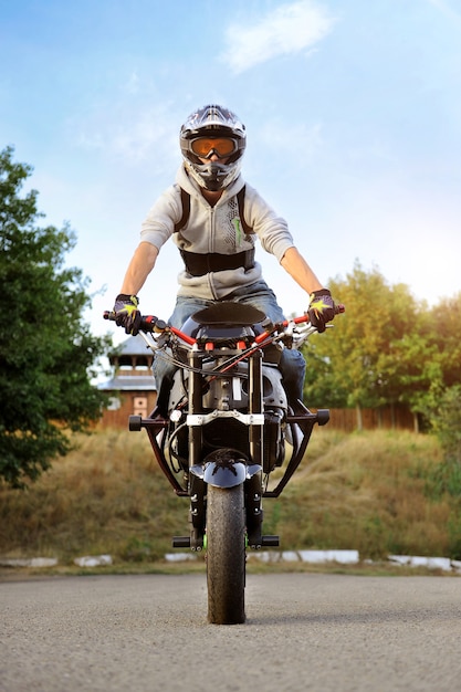 Vertikales Foto des jungen starken Radfahrers, der auf Sportmotorrad sitzt.