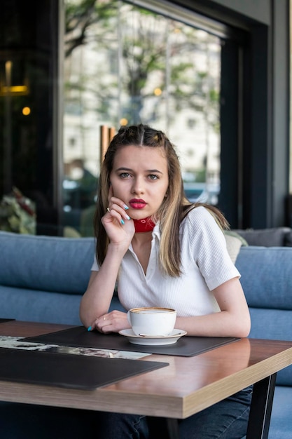 Vertikales Foto einer jungen Dame, die im Restaurant sitzt und in die Kamera schaut