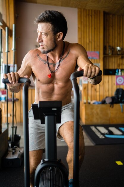 Vertikales Foto eines Mannes, der ein Airbike in einem Fitnessstudio benutzt