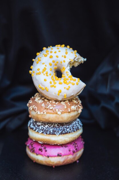 Vertikales Foto eines süßen Donuts Farbiger Haufen köstlicher Donuts