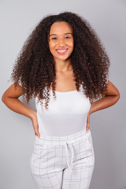 Vertikales Foto schöne schwarze Brasilianerin in weißer Freizeitkleidung lächelnd