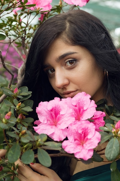 Vertikales Foto, verträumtes Mädchen unter blühenden Rosenbüschen. Hochwertiges Foto