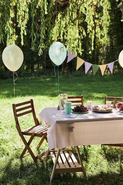 Foto vertikales hintergrundbild des sommer-picknick-tisches im freien mit luftballons für die geburtstagsfeier geschmückt...