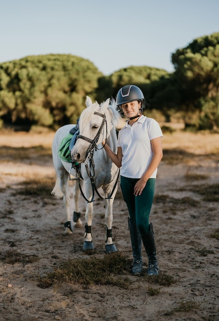 Vertikales Porträt eines 12-jährigen Kinderreiters mit weißem Pony