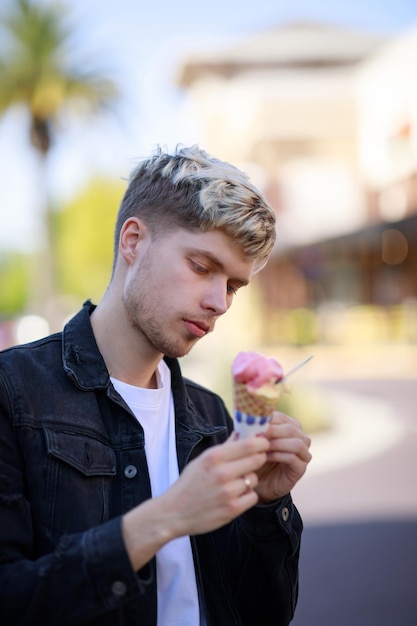 Vertikales Porträt eines jungen gutaussehenden Mannes mit Eiscreme