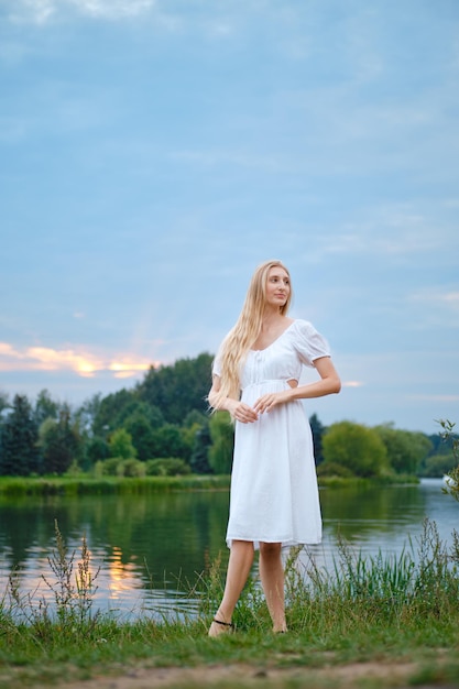 Verträumte junge Frau am Abend am Fluss