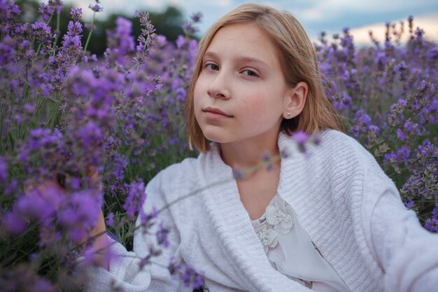 Verträumtes Teenagermädchen sitzt in Lavendelfeldschönheit der Natursommerlebensstilruhelandschaft