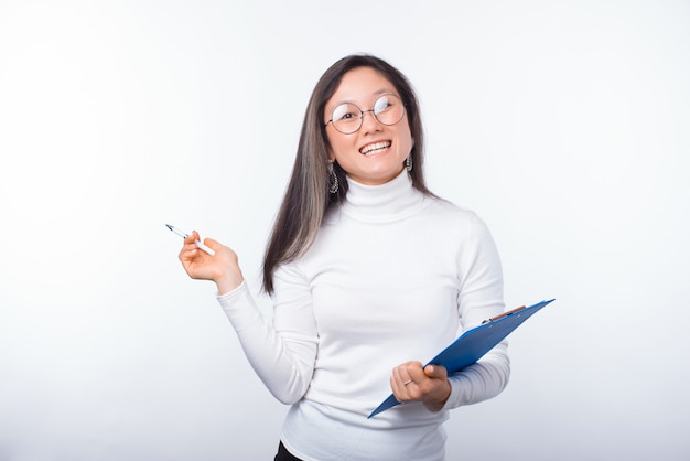 Vervollständigen wir die Checkliste. Das Porträt einer fröhlichen jungen Frau hält eine Pappe und einen Stift.