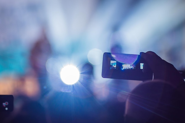 Verwenden Sie fortschrittliche mobile Aufnahmen für unterhaltsame Konzerte und schöne Beleuchtung Unverfälschtes Bild der Menge bei einem Rockkonzert Nahaufnahme einer Videoaufnahme mit dem Smartphone Genießen Sie die Verwendung mobiler Fotografie