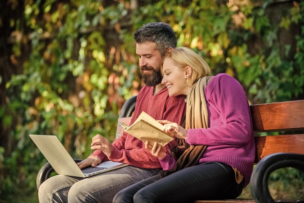 Verwenden Sie sowohl digitale Ansätze als auch Bücher Mann und Frau verwenden unterschiedliche Informationsspeicherung Paar verbringt Freizeit mit Lesen Paar mit Buch- und Laptop-Suchinformationen Informationsquellenkonzept