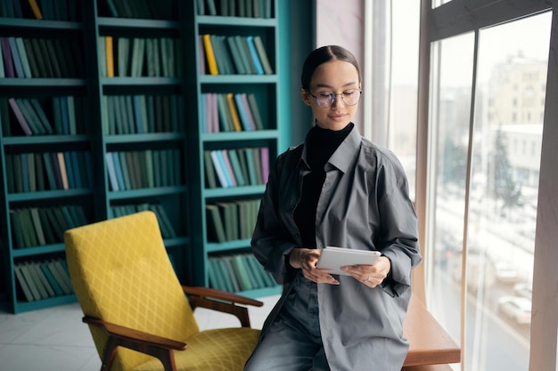 Verwendet ein Tablet eine Frau mit Brille, die der Manager im Büro des Konzeptbüros arbeitet