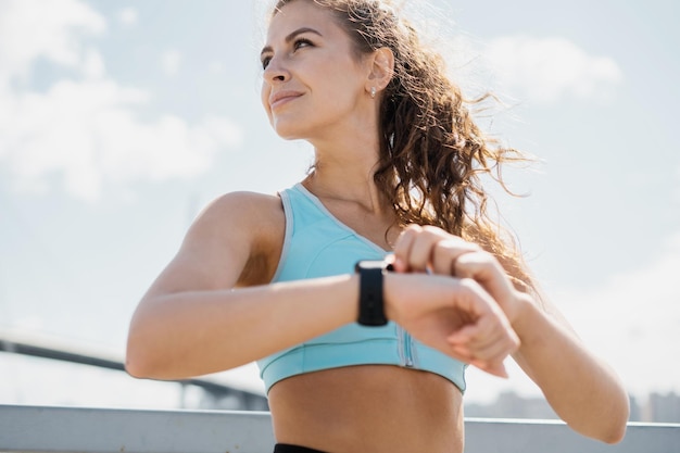 Verwendet eine Puls-Smartwatch, sportlich selbstbewusste Frau, aktives Outdoor-Training, Laufen und Aufwärmen des Körpers