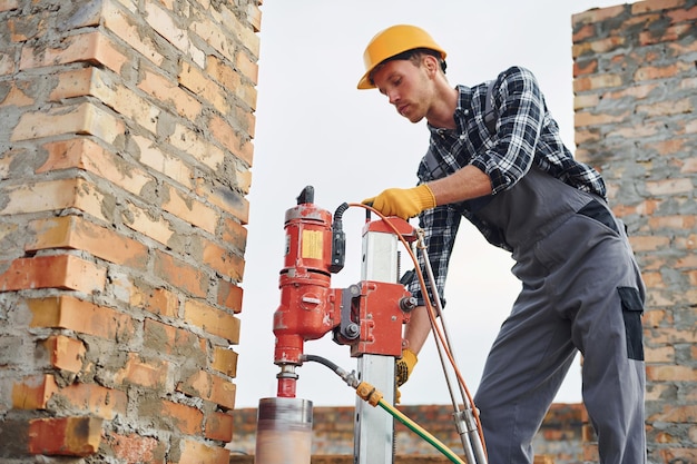 Verwendet Mischbohrer Bauarbeiter in Uniform und Sicherheitsausrüstung haben Arbeit am Bau