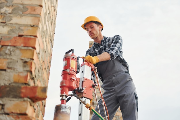 Verwendet Mischbohrer Bauarbeiter in Uniform und Sicherheitsausrüstung haben Arbeit am Bau