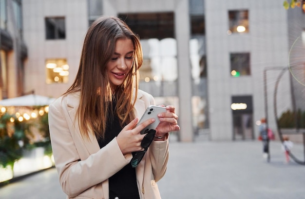 Verwendet Telefon Schöne junge europäische Frau ist tagsüber draußen in der Stadt