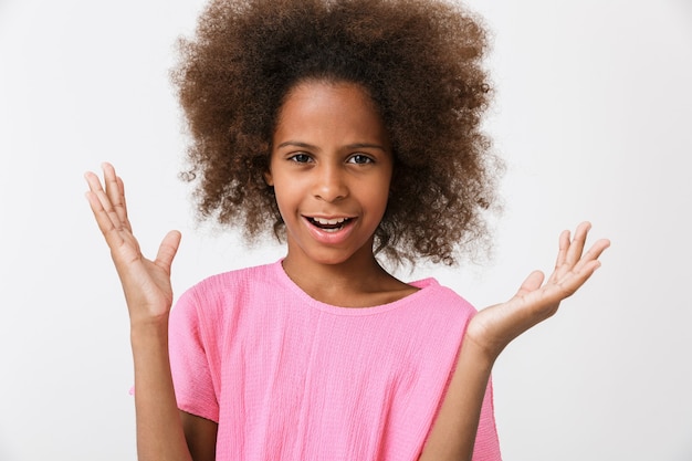 Verwirrtes kleines afrikanisches Mädchen mit rosa Bluse steht isoliert über weißer Wand und zuckt mit den Schultern