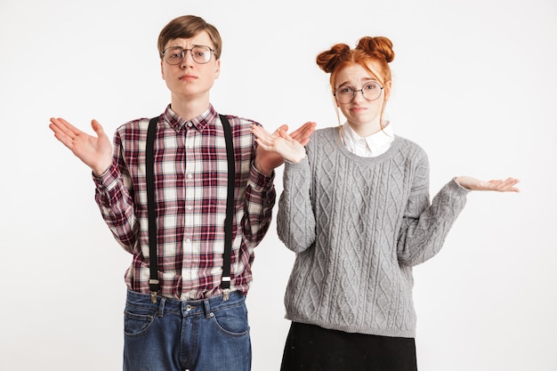 Foto verwirrtes schul-nerd-paar zuckt die achseln