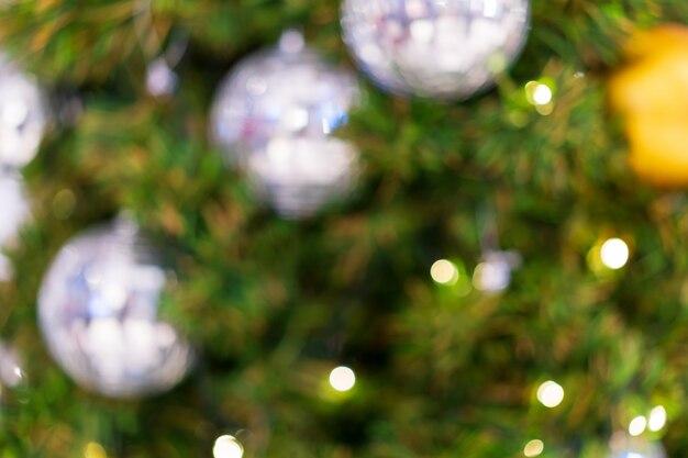 Foto verwischt vom grünen weihnachtsbaum eingerichtet und dekoriert mit silber glänzendem x'mas ball und warmem licht