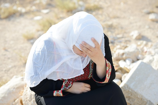 Verzweifelte arabische Frau sitzt auf Felsen und weint